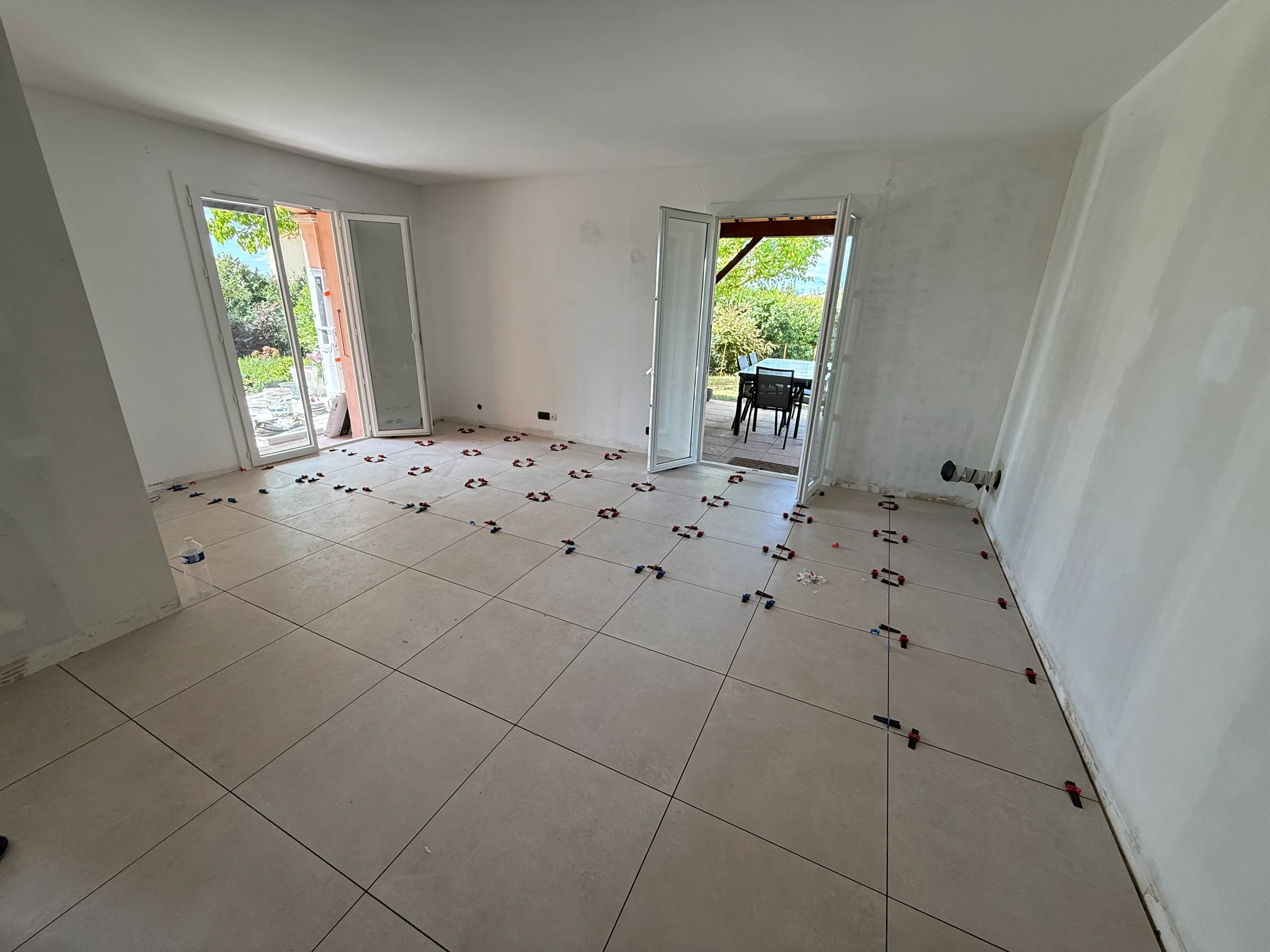 Séjour du rez-de-chaussée en travaux, avec carrelage en cours de pose et murs en préparation