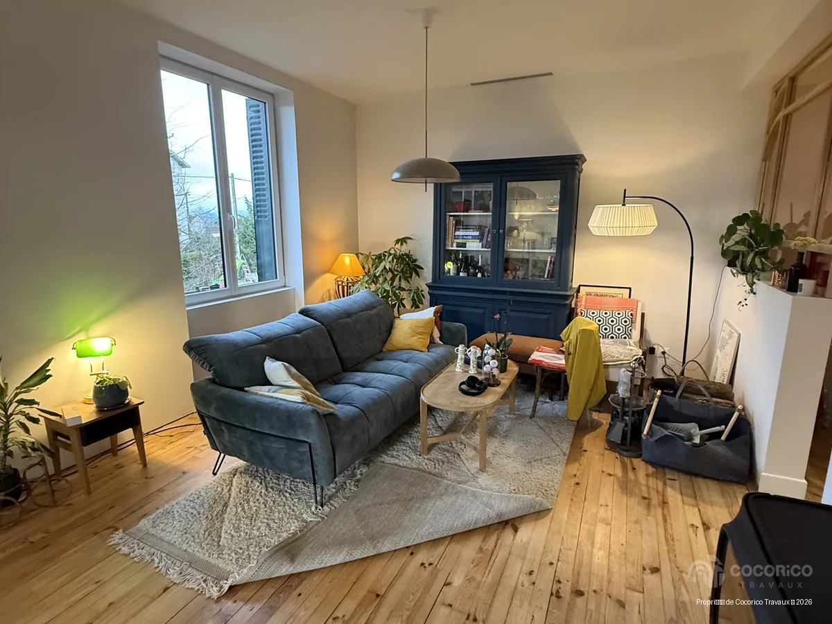 Salon d’une maison des années 30 rénovée à Romans-sur-Isère, avec parquet et canapé bleu.